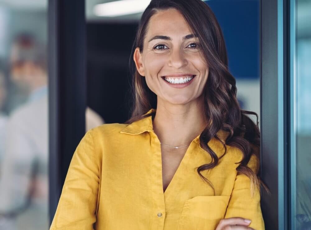 Teaserbild der Startseite, das eine fröhliche Frau im Büro zeigt